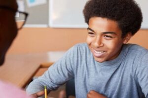 a boy smiling at a desk