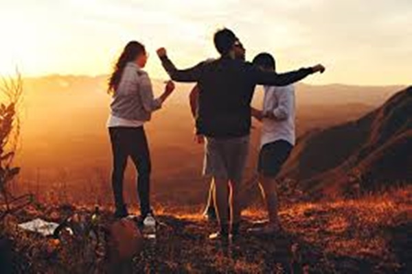 a group of people standing on a hill with their arms raised